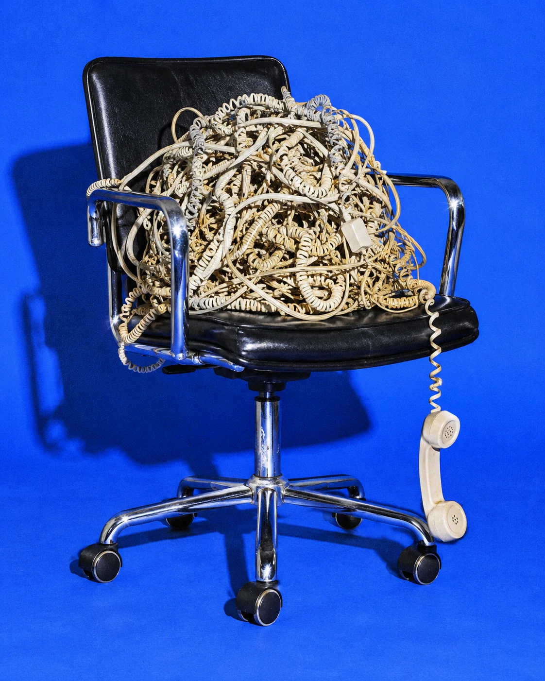 An office chair taken over by a tangle of telephone cords
